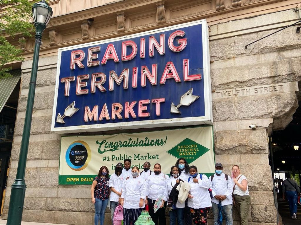Students standing in front of reading terminal market sign