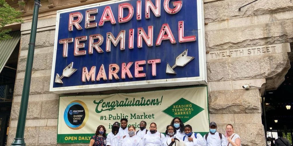 Students standing in front of reading terminal market sign